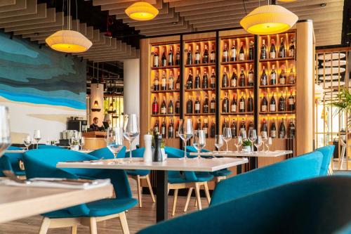 a restaurant with tables and blue chairs and wine bottles at Seaside Park Hotel in Kołobrzeg