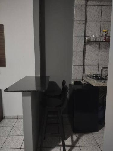 a kitchen with a black counter and a stool at Quarto aconchegante Completo in Rio Branco