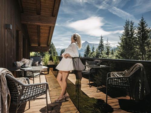 Una mujer parada en un balcón con vistas a las montañas en Hotel Bergkristall Zillertal en Hippach