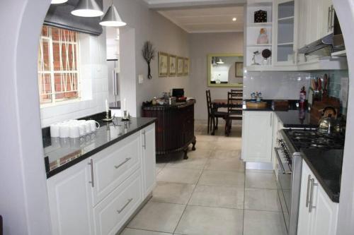 a large kitchen with white cabinets and a dining room at Green Acres Country House in Lidgetton