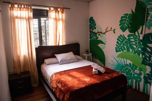 1 dormitorio con 1 cama en una habitación con un mural en Kimaná Hostal, en Santa Rosa de Cabal