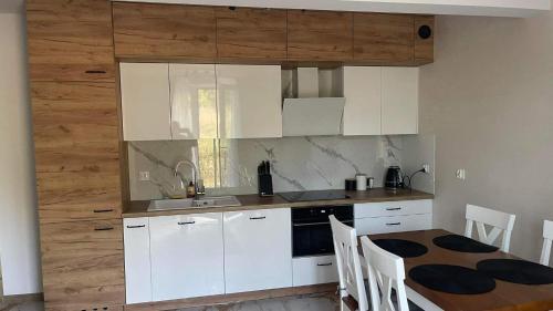 a kitchen with white cabinets and a table with chairs at Apartament Niebieski 14/1 in Starogard Gdański