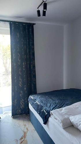 a bedroom with a bed with a black curtain and a window at Apartament Niebieski 14/1 in Starogard Gdański