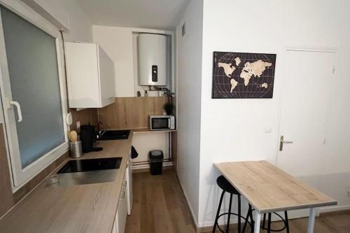 une cuisine avec des armoires blanches et une table en bois dans l'établissement Au P’tit Écureuil - Studio hypercentre Rouen, à Rouen