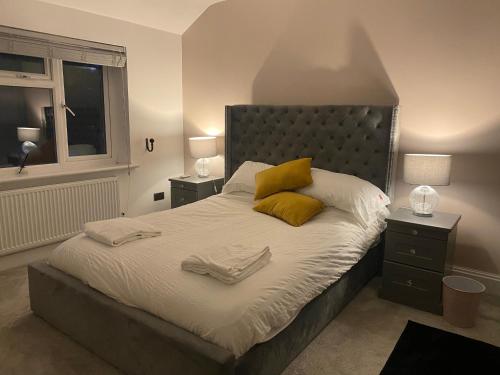1 dormitorio con 1 cama grande con almohadas amarillas en Spacious family friendly 3 bedroom Home With Hot tub & 75tv, en Potters Bar