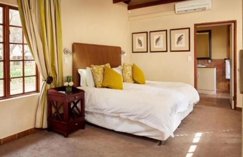 una camera da letto con un grande letto bianco con cuscini gialli di Unit H011 Magalies Park Hartbeespoort a Hartbeespoort
