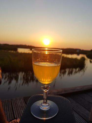 a glass of wine sitting on a table with the sunset at Walvisch van Ghyspe in Wormer