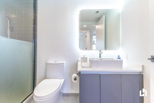 a bathroom with a toilet and a sink and a mirror at Downtown Miami Condos by Lua Host in Miami