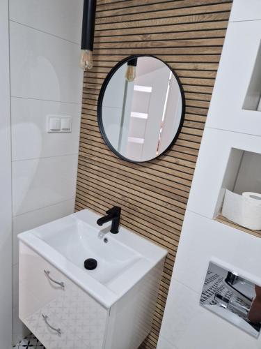 La salle de bains est pourvue d'un lavabo blanc et d'un miroir. dans l'établissement Apartament Staromiejski Rapackiego 45, à Grudziądz