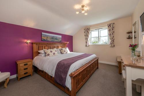 ein Schlafzimmer mit einem Bett und einer lila Wand in der Unterkunft Countryside cottage in tranquil surroundings in Broadwoodwidger