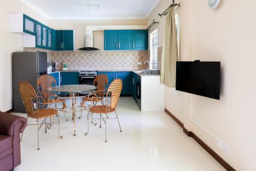 cocina con armarios azules, mesa y sillas en ibis Apartments - Ground Floor - Summersun Residence - Grand Baie, Pereybere en Grand Baie