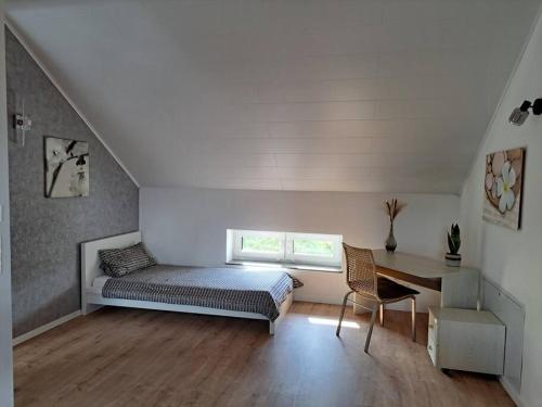 a bedroom with a bed and a desk and a window at Juliane`s Panorama-Domizil in Nemmersdorf in Goldkronach