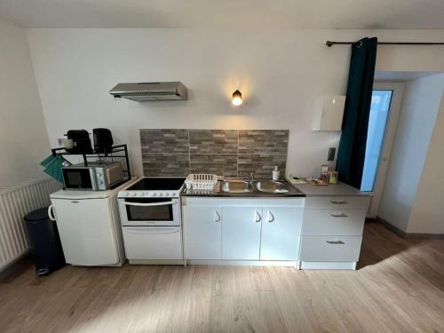 a kitchen with white cabinets and a stove top oven at Le Dauphin - Appartement chaleureux proche Gare de Bourgoin in Jallieu