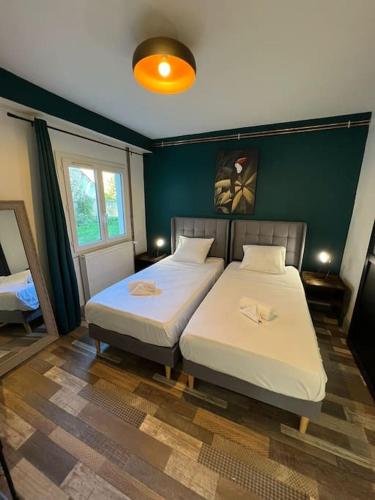 - une chambre avec 2 lits et un mur vert dans l'établissement Le Dauphin - Appartement chaleureux proche Gare de Bourgoin, à Jallieu