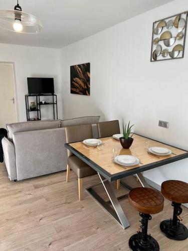 une salle à manger avec une table, des chaises et un canapé dans l'établissement Le Dauphin - Appartement chaleureux proche Gare de Bourgoin, à Jallieu