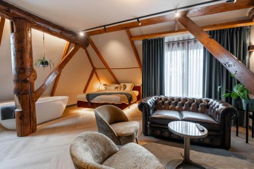 a bedroom with a bed and a couch and a chair at Boetiekhotel Faan in Ballum