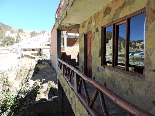 TITI QALA HOSTEL في Comunidad Challapampa: مبنى به نافذتين وشرفة
