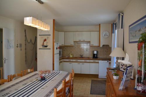 - une cuisine avec des placards blancs, une table et des chaises dans l'établissement Les Floralies, à La Tranche-sur-Mer