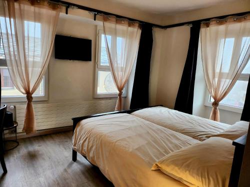 a bedroom with a bed and two windows at Auberge de l’Union in Lens