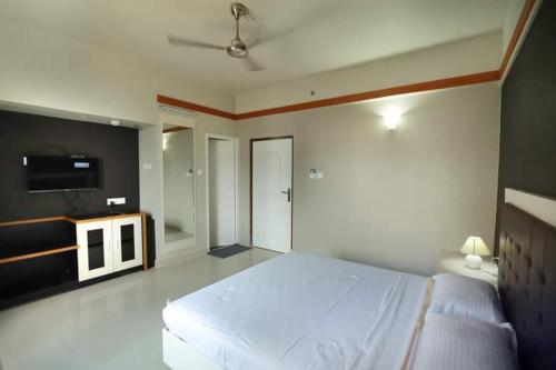 1 dormitorio con 1 cama blanca grande y TV en VS RESIDENCY en Mūvattupula