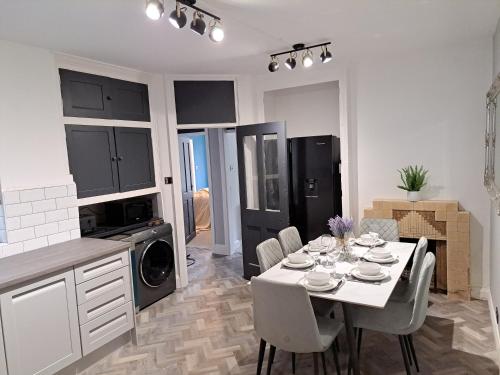 a kitchen and dining room with a white table and chairs at Kingsdown Apartment in Great Malvern