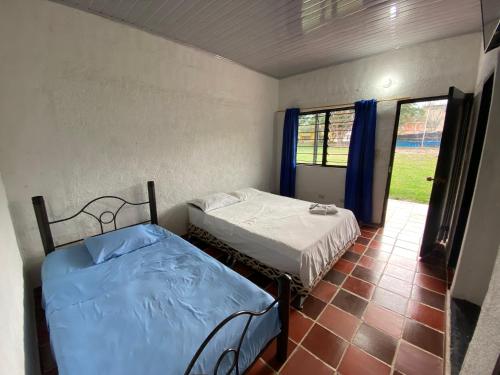 two beds in a room with a window at El Palmar in Guaduas