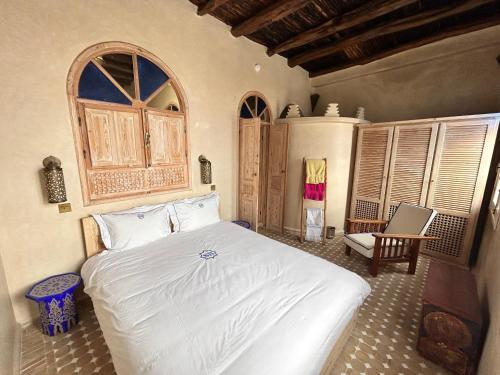 a bedroom with a white bed and a window at Beau riad en médina, lumineux et avec terrasse privée sur mer in Essaouira