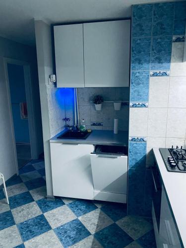 a kitchen with white cabinets and a blue tile floor at Mieszkanie blisko dworca PKP in Radom