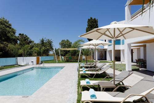 a swimming pool with lounge chairs and umbrellas at Coconut Palm Paradise in Gállos