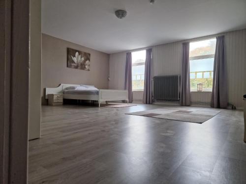 an empty room with a bed and two windows at B&B 't Kloaster kamer Het Landhuis in Hulsberg