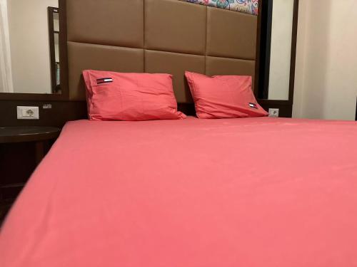 a bed with pink sheets and two red pillows at Porto Sharm-Elsheikh in Sharm El Sheikh