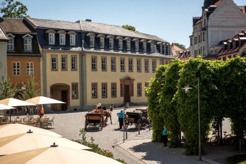 a large building with tables and umbrellas in a courtyard at Hotel am Goethehaus in Weimar