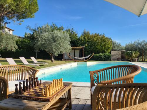 una piscina con due panche in legno e una scacchiera accanto di Villa with Pool and Countryside View a Montefalco