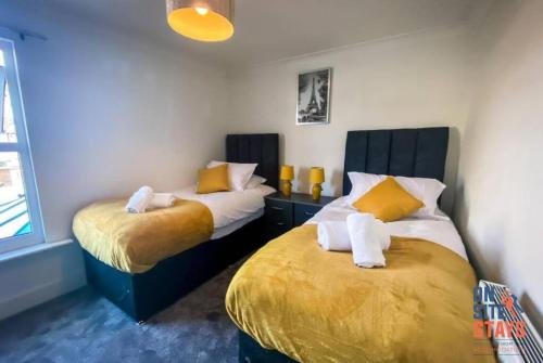 a bedroom with two beds with yellow and white pillows at OnSiteStays - Contractor Friendly Retreat, 2-BR Terrace House near A2 in Gravesend