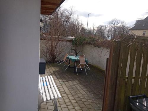 eine Terrasse mit einem Tisch, Stühlen und einem Zaun in der Unterkunft City Pension Senftenberg / Apartment Nr.1 in Senftenberg