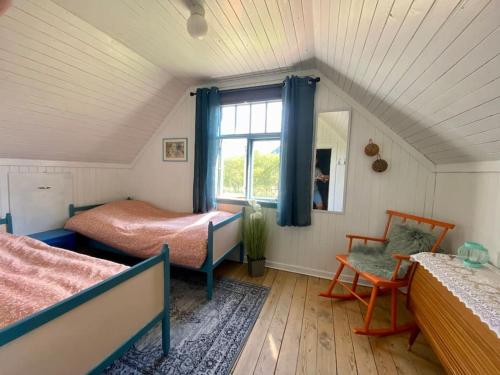 a bedroom with two beds and a window and a chair at Villa Reipå - Northern lights and midnight sun in Reipå