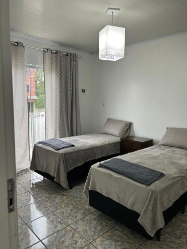 een slaapkamer met 2 bedden en een raam bij 1o Andar in Canoinhas