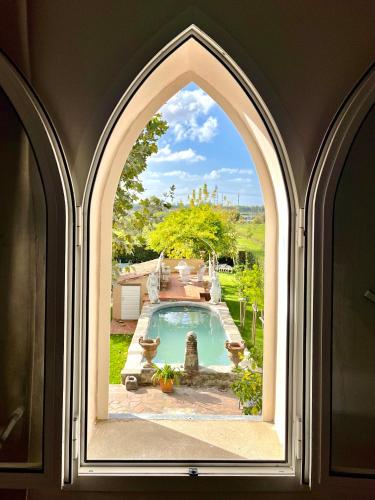 an arched window looking out at a swimming pool at B&B Ninfeo dell' Arancera in Calci
