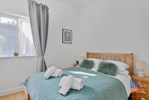 a bedroom with a bed with towels on it at OnSiteStays - Tranquil 2 Bedroom Apartment with Large Kitchen, Private Garden near Wimbledon Station in London