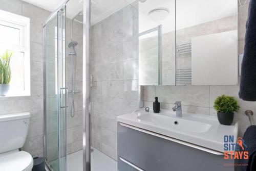 a bathroom with a sink and a glass shower at OnSiteStays - Tranquil 2 Bedroom Apartment with Large Kitchen, Private Garden near Wimbledon Station in London