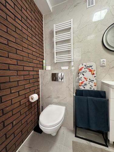 bagno con servizi igienici bianchi e parete in mattoni di Apartamenty 1-maja 94 a Katowice