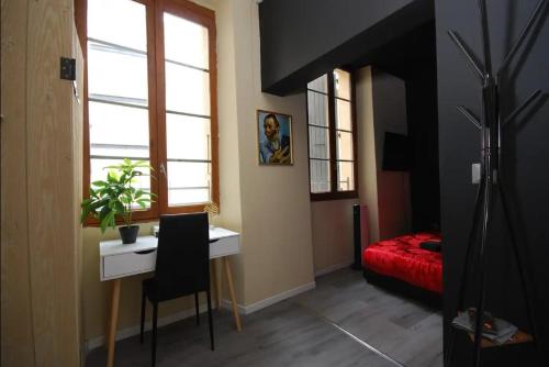 Habitación con escritorio, cama y ventana. en Baignoire Cosy Centre Narbonne en Narbona