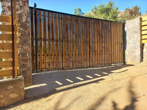 a gate with a wooden fence in a driveway at Cabaña valle de elqui horcon Encantó del pimiento in Horcon