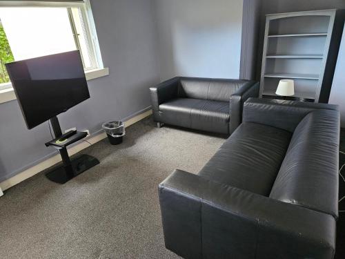 a living room with a leather couch and a chair at Cunninghame 3 in Beith