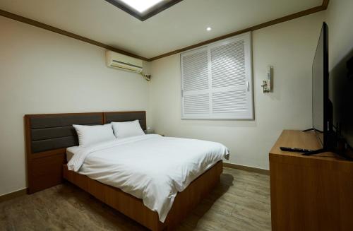 a bedroom with a bed and a flat screen tv at Buan Tree California Hotel in Buan