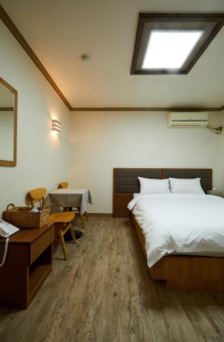 a bedroom with a bed and a desk and a window at Buan Tree California Hotel in Buan