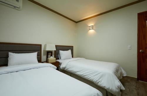 two beds in a hotel room with white sheets at Buan Tree California Hotel in Buan