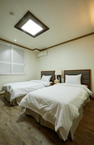 a bedroom with two beds with white sheets and a skylight at Buan Tree California Hotel in Buan
