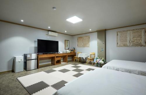 a bedroom with two beds and a desk with a television at Buan Tree California Hotel in Buan