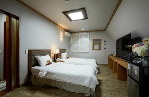 a hotel room with two beds and a flat screen tv at Buan Tree California Hotel in Buan